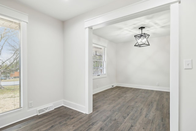 interior space featuring dark wood-style flooring, visible vents, a notable chandelier, and baseboards