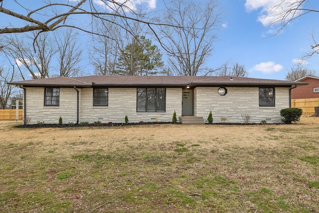 ranch-style house with roof with shingles, fence, and a front yard