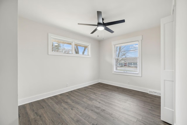 spare room featuring ceiling fan, dark wood-type flooring, visible vents, and baseboards