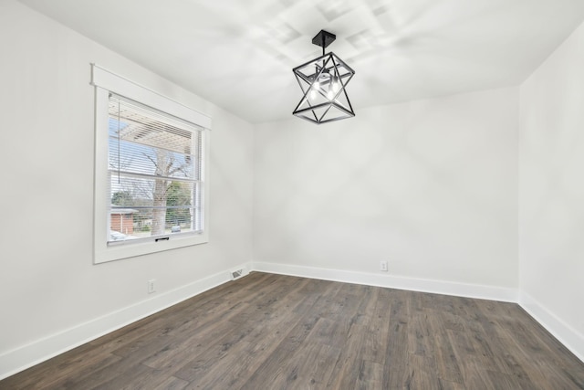 unfurnished dining area with dark wood-style floors, visible vents, a notable chandelier, and baseboards