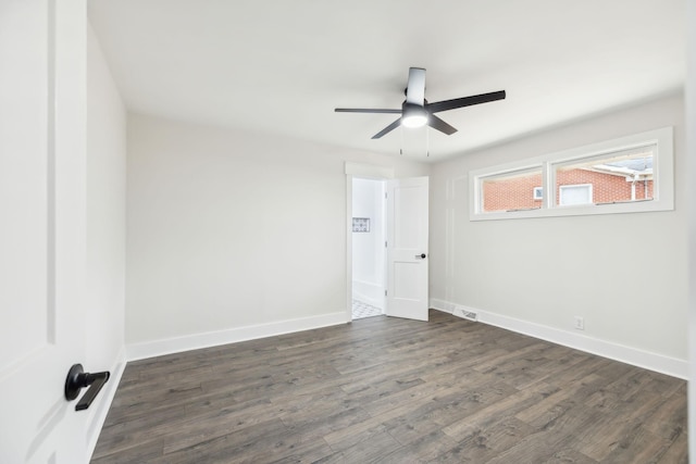 unfurnished room featuring dark wood-style floors, a ceiling fan, visible vents, and baseboards