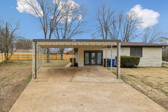 exterior space with stone siding, french doors, driveway, and fence