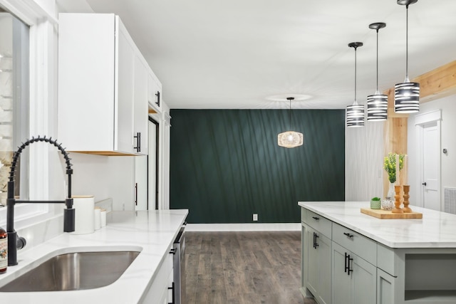 kitchen featuring pendant lighting, dark wood finished floors, gray cabinets, a sink, and light stone countertops