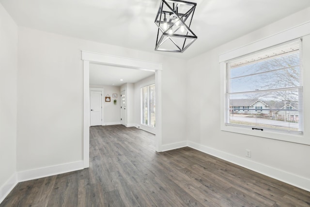 unfurnished dining area featuring dark wood finished floors and baseboards