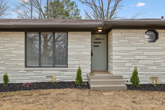 property entrance featuring crawl space, stone siding, and roof with shingles