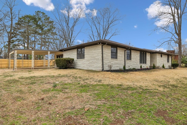 view of side of home featuring a yard, fence, and a carport