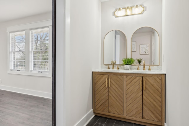 bathroom featuring wood finished floors, a sink, baseboards, and double vanity