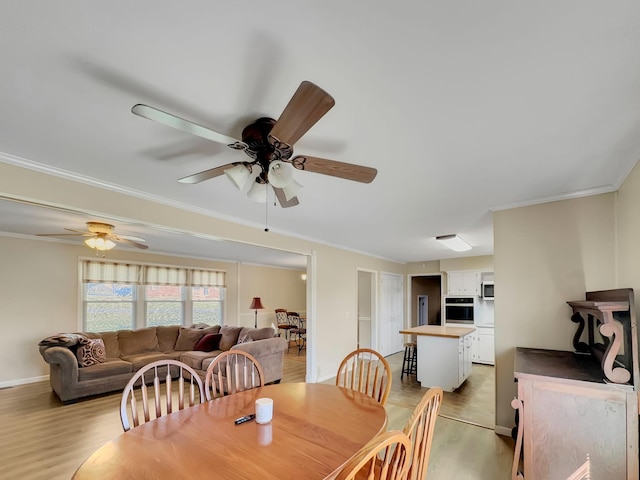 dining area featuring a ceiling fan, baseboards, crown molding, and light wood finished floors