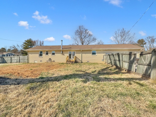 back of house featuring brick siding, a lawn, entry steps, crawl space, and a fenced backyard