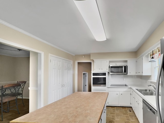 kitchen with light countertops, appliances with stainless steel finishes, a sink, and white cabinetry