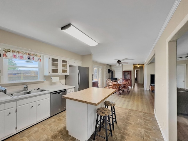 kitchen featuring stainless steel appliances, stone finish flooring, a sink, and a kitchen breakfast bar