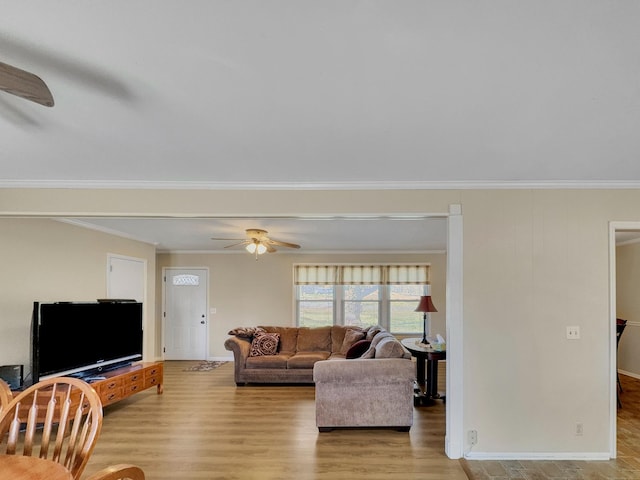 living area with baseboards, wood finished floors, a ceiling fan, and crown molding