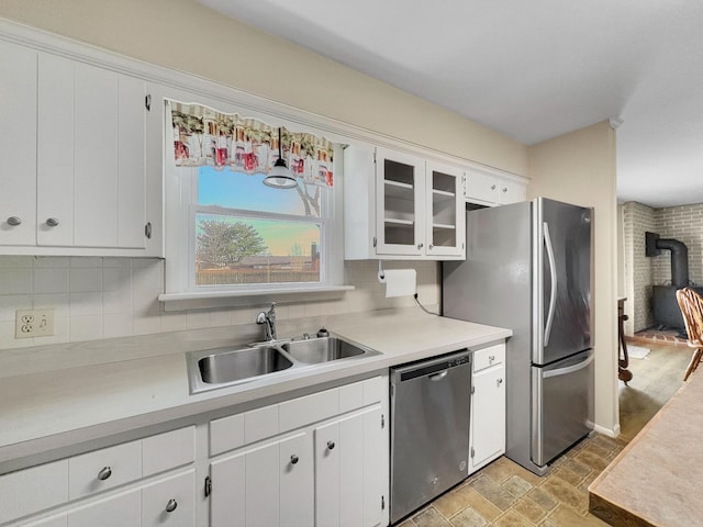 kitchen featuring appliances with stainless steel finishes, light countertops, a sink, and backsplash