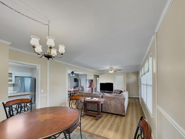 dining room with ceiling fan with notable chandelier, light wood-style flooring, and crown molding