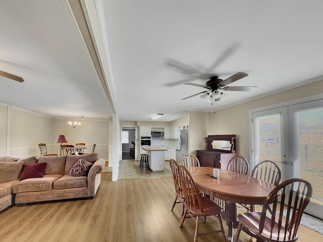 dining area featuring french doors, plenty of natural light, light wood finished floors, and ceiling fan with notable chandelier