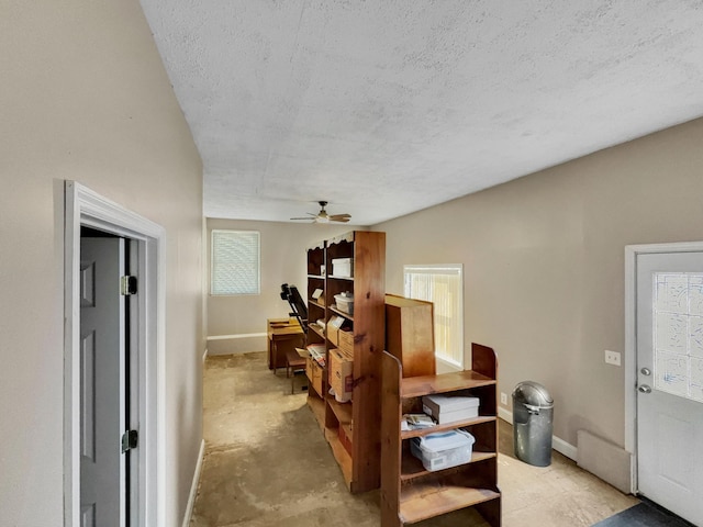 interior space with unfinished concrete flooring, a textured ceiling, and baseboards