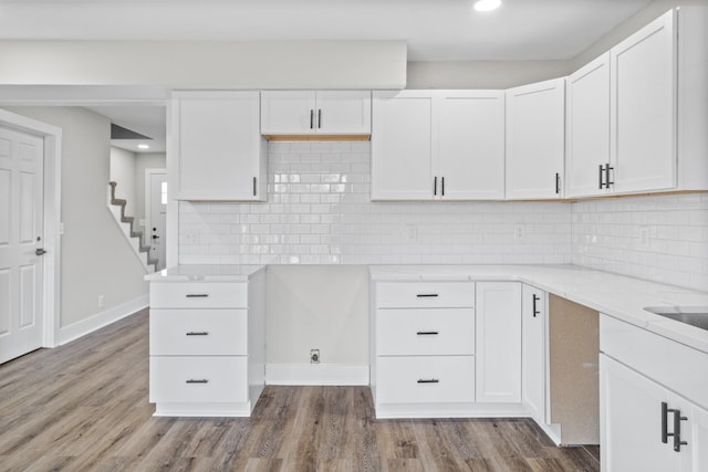 kitchen featuring white cabinetry, decorative backsplash, and wood finished floors