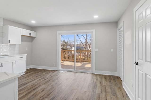 unfurnished dining area with recessed lighting, light wood-style flooring, and baseboards