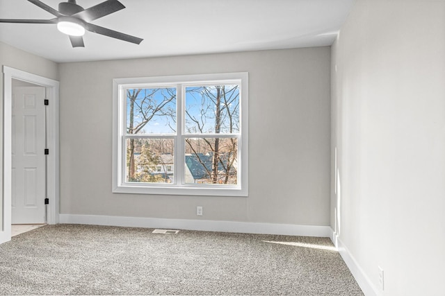 carpeted spare room with visible vents, baseboards, and a ceiling fan