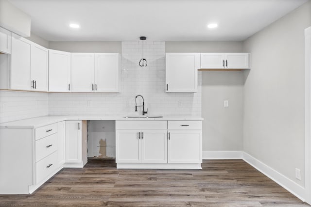 kitchen featuring tasteful backsplash, white cabinetry, a sink, and wood finished floors