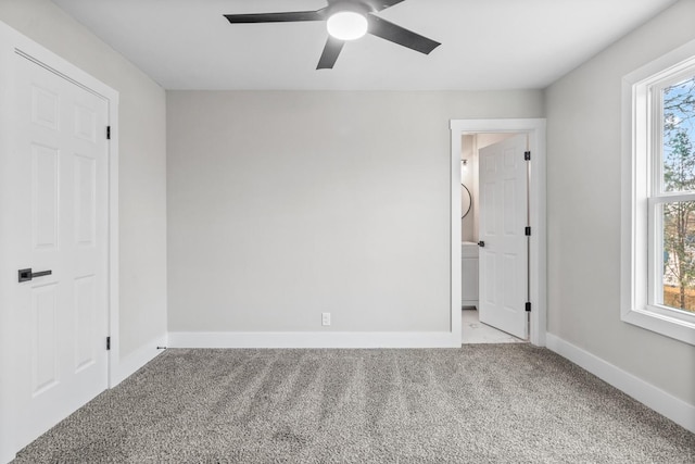 unfurnished bedroom with multiple windows, carpet, a ceiling fan, and baseboards