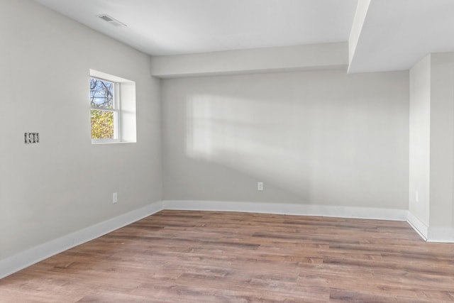 empty room with visible vents, baseboards, and wood finished floors