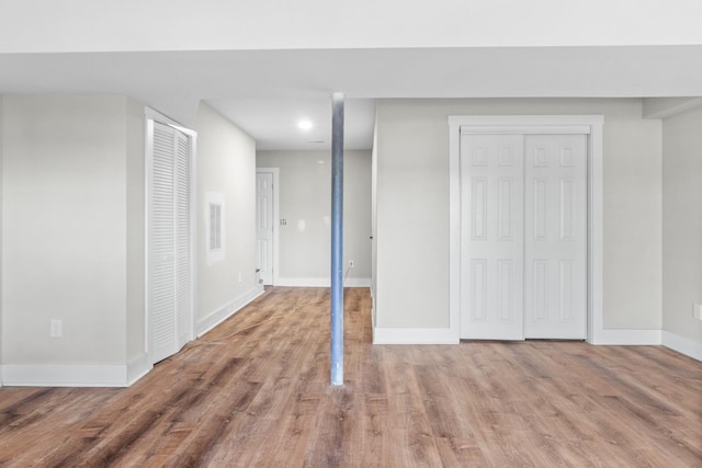 unfurnished bedroom featuring two closets, wood finished floors, visible vents, and baseboards