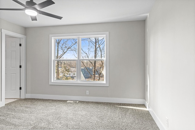 carpeted spare room featuring visible vents, ceiling fan, and baseboards