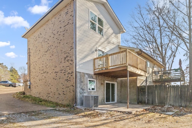 back of house featuring a patio, central AC, brick siding, fence, and a wooden deck