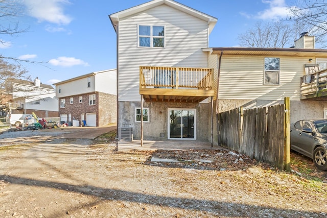 rear view of house with a chimney, a patio area, fence, a balcony, and cooling unit