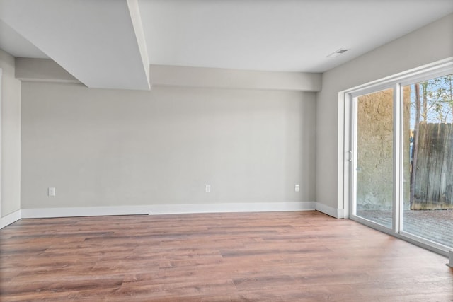 spare room featuring visible vents, baseboards, and wood finished floors