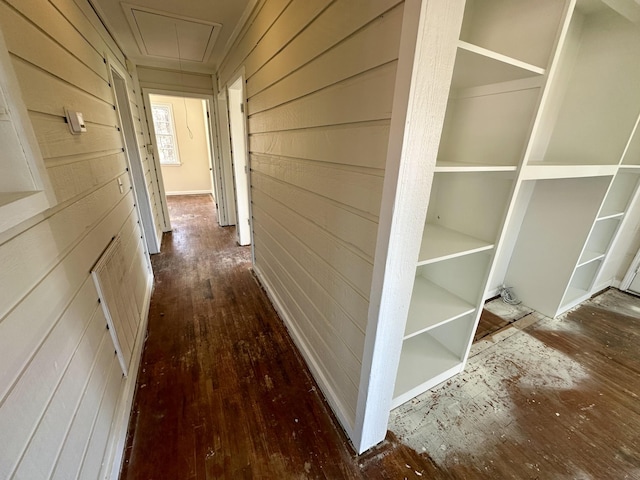 hall featuring attic access, wooden walls, and wood-type flooring