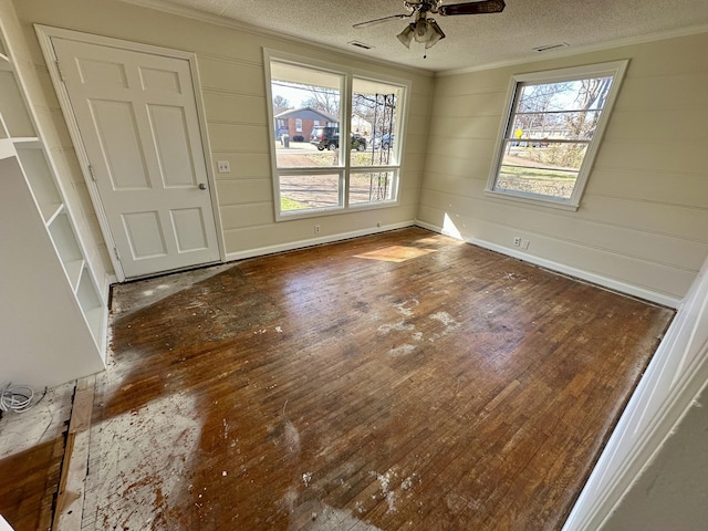 spare room with ornamental molding, a healthy amount of sunlight, and hardwood / wood-style flooring