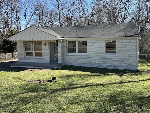 view of front of home featuring stone siding, a shingled roof, fence, and a front yard