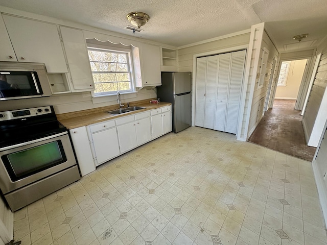 kitchen featuring white cabinets, stainless steel appliances, light countertops, light floors, and a sink