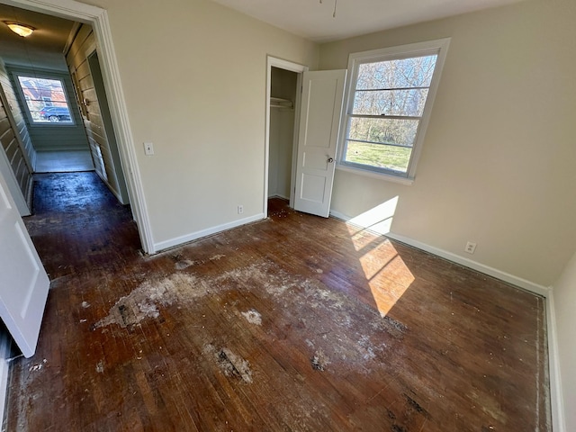 unfurnished bedroom featuring a closet, wood-type flooring, and baseboards