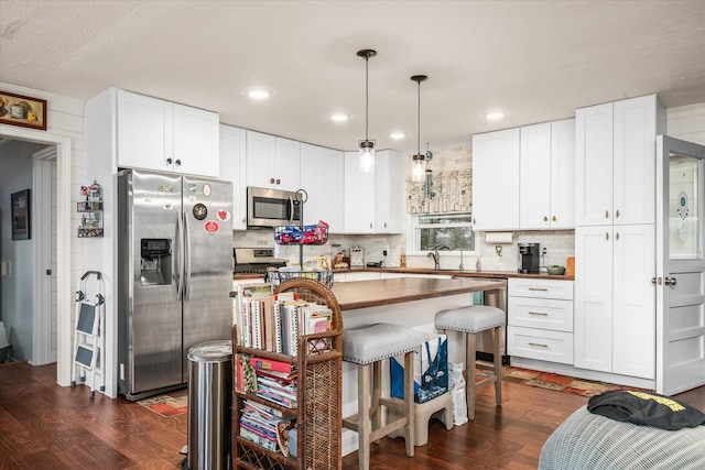 kitchen with stainless steel appliances, white cabinets, a kitchen breakfast bar, and dark wood-style floors