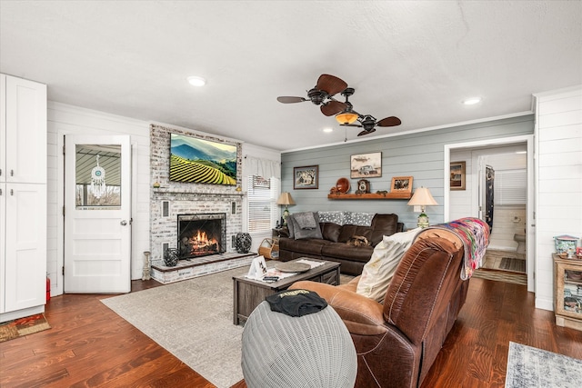 living room with ceiling fan, recessed lighting, a fireplace, ornamental molding, and dark wood finished floors