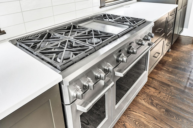 interior details featuring light countertops, range with two ovens, dark wood finished floors, and tasteful backsplash