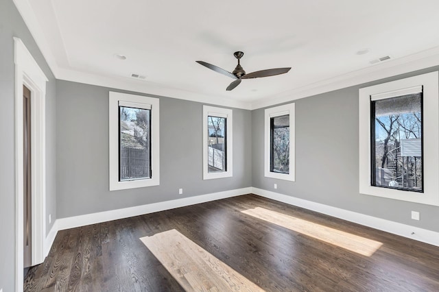 spare room with dark wood-style floors, visible vents, ornamental molding, and baseboards