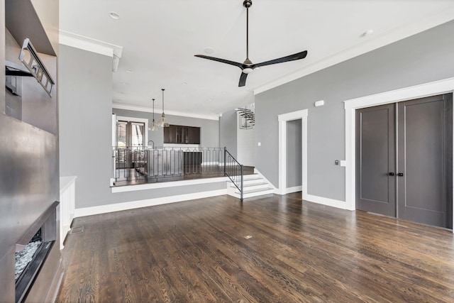 unfurnished living room featuring a ceiling fan, baseboards, crown molding, and wood finished floors