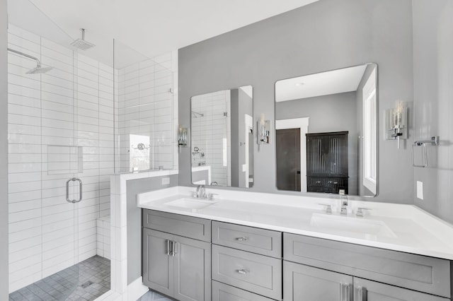 bathroom featuring double vanity, a stall shower, and a sink