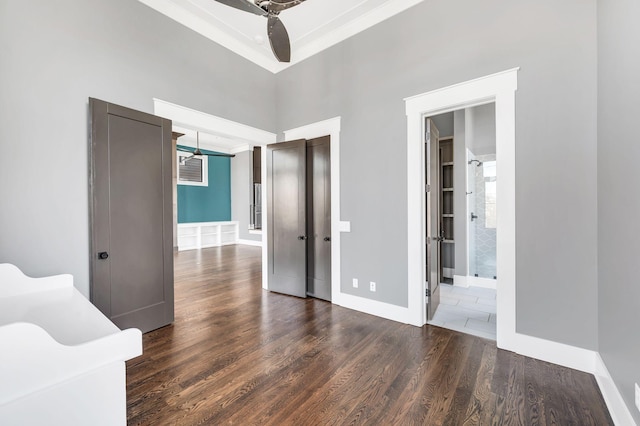 unfurnished bedroom with ensuite bath, baseboards, and wood finished floors