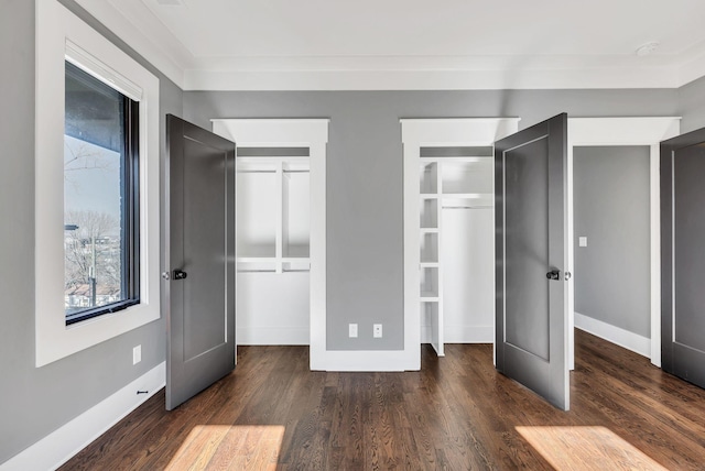 unfurnished bedroom featuring multiple windows, baseboards, and wood finished floors