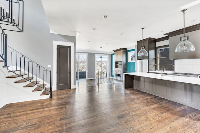 kitchen with dark wood-style floors, pendant lighting, light countertops, decorative backsplash, and a sink