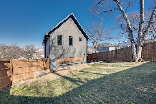 back of house featuring a fenced backyard, a lawn, and brick siding