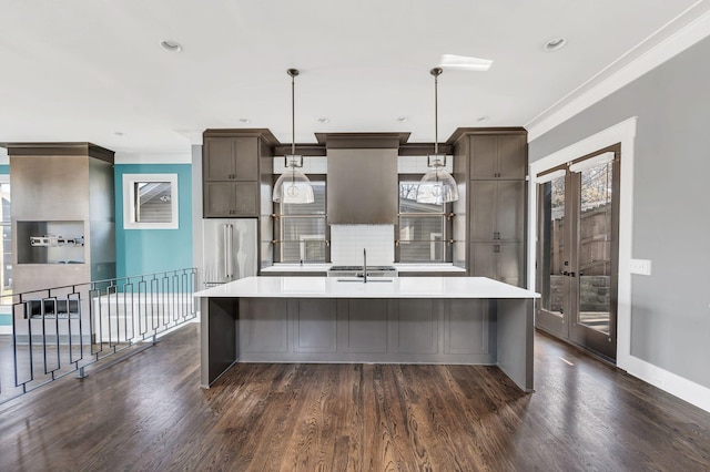 kitchen with a kitchen island with sink, high quality fridge, light countertops, and a sink