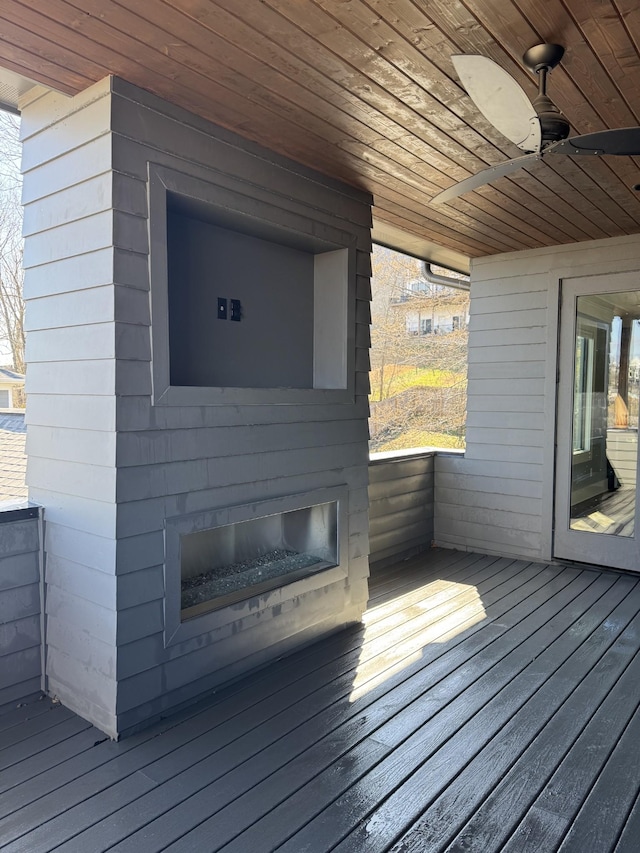 wooden terrace with ceiling fan and a glass covered fireplace