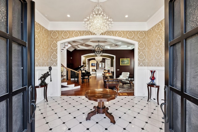 entryway with an inviting chandelier, arched walkways, and wallpapered walls