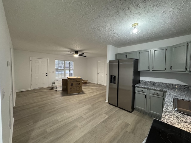 kitchen with cooktop, gray cabinets, stainless steel refrigerator with ice dispenser, and light wood finished floors